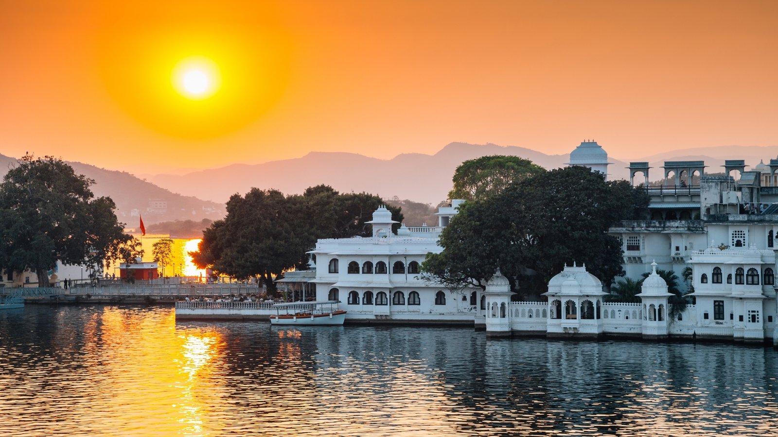 Gangaur Ghat in Udaipur glowing at dusk, with reflections dancing on Lake Pichola.