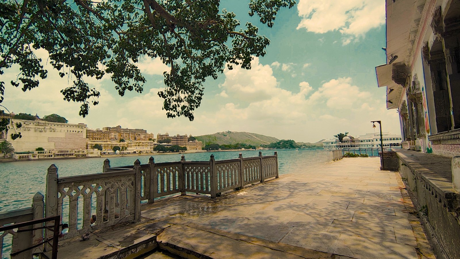 Ambrai Ghat in Udaipur at sunset, with golden reflections on Lake Pichola and City Palace glowing across the water