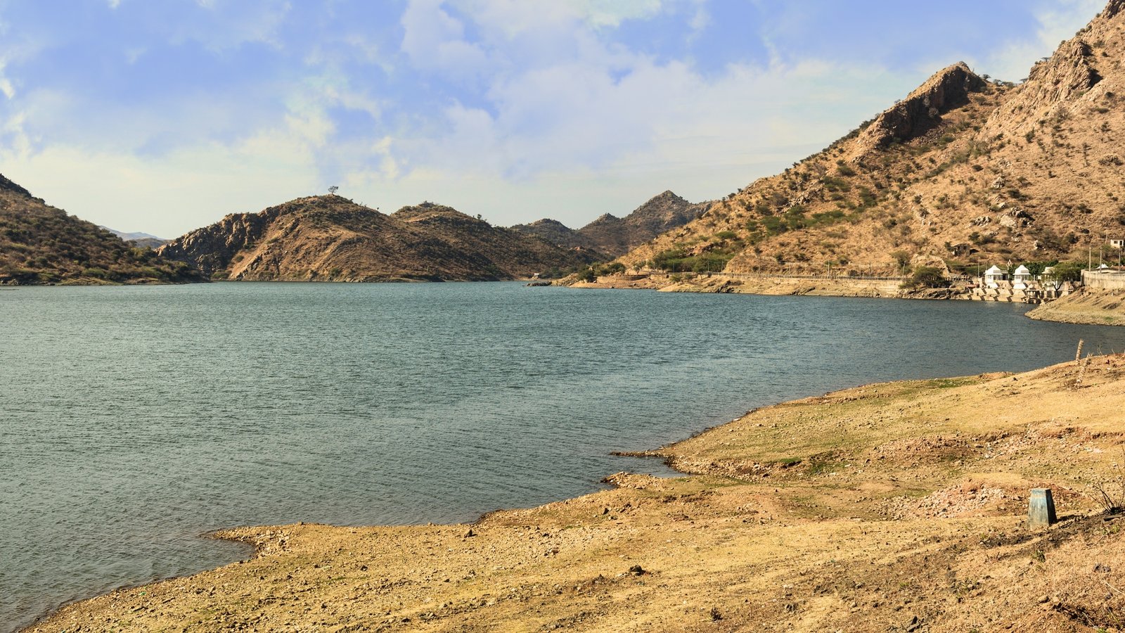 Badi Lake in Udaipur surrounded by lush Aravalli hills, reflecting the sky in tranquil ripples