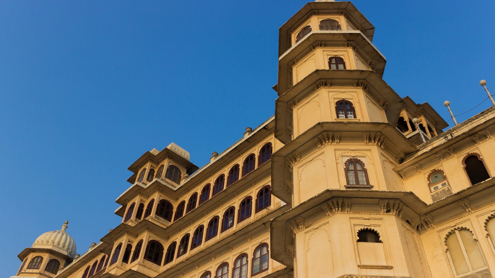 City Palace in Udaipur illuminated at twilight, showcasing its majestic domes and lakeside architecture