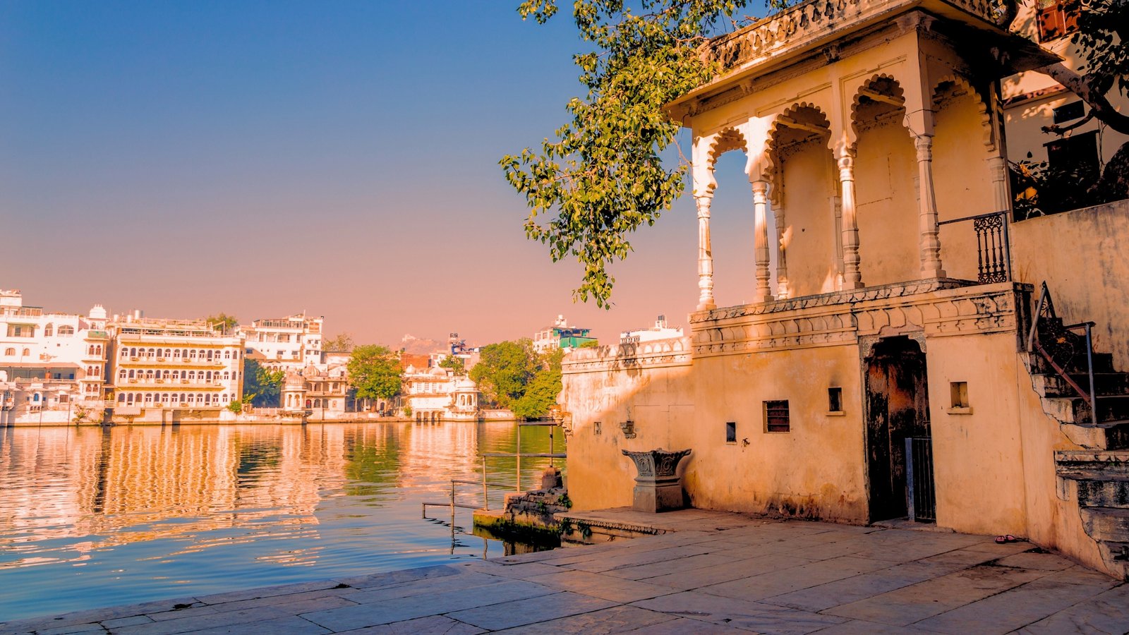 Gangaur Ghat in Udaipur glowing at dusk, with reflections dancing on Lake Pichola.