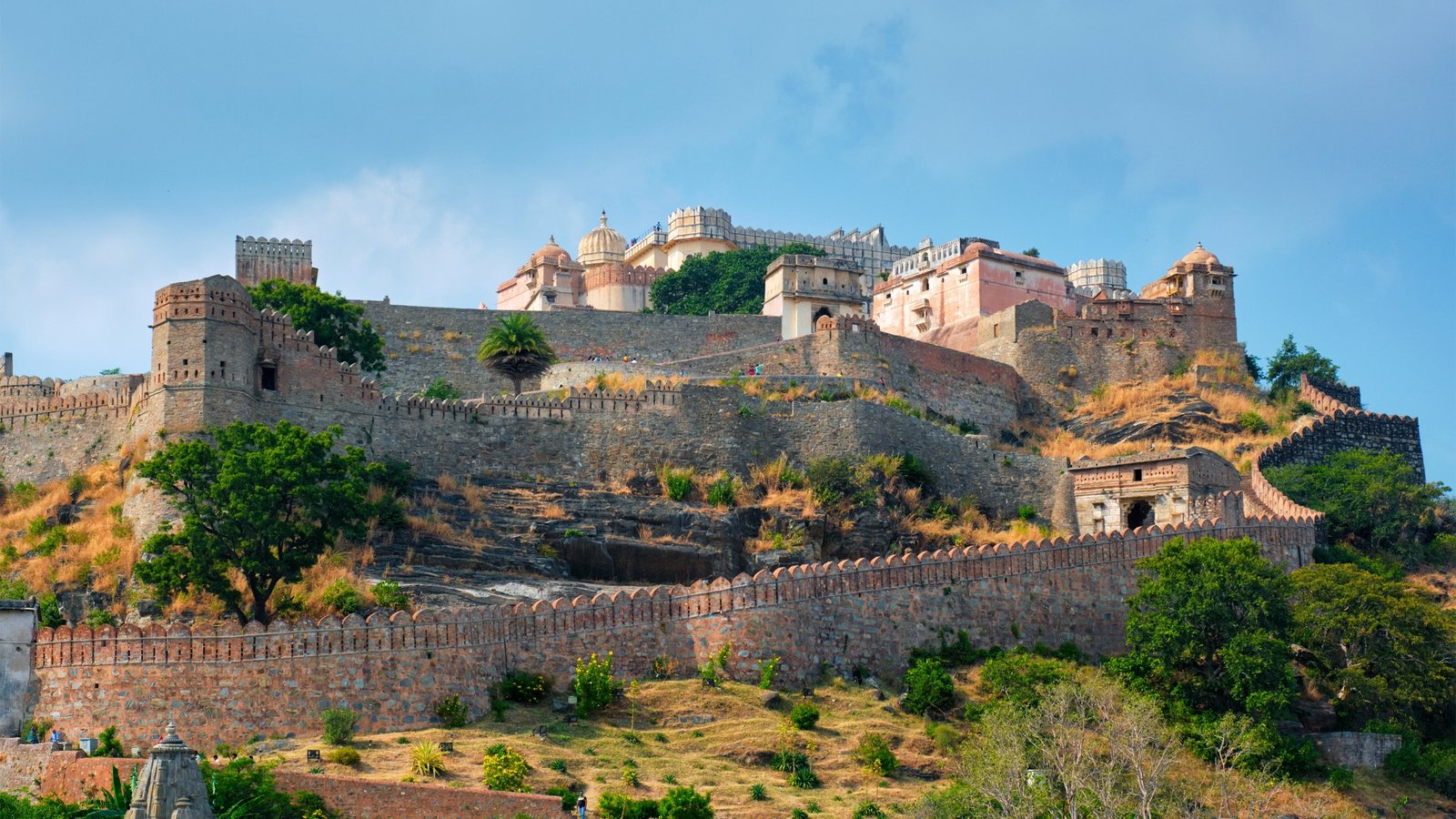 Kumbhalgarh Fort in Rajasthan, with its massive stone ramparts winding through the Aravalli hills, crowned by ancient bastions and temples.
